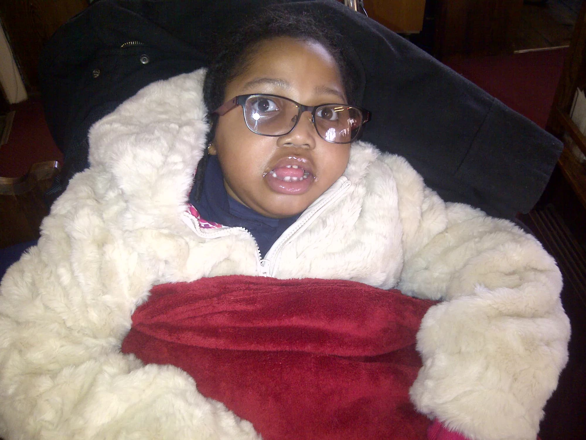 Abigail wrapped warmly in a pale coat and blanket.