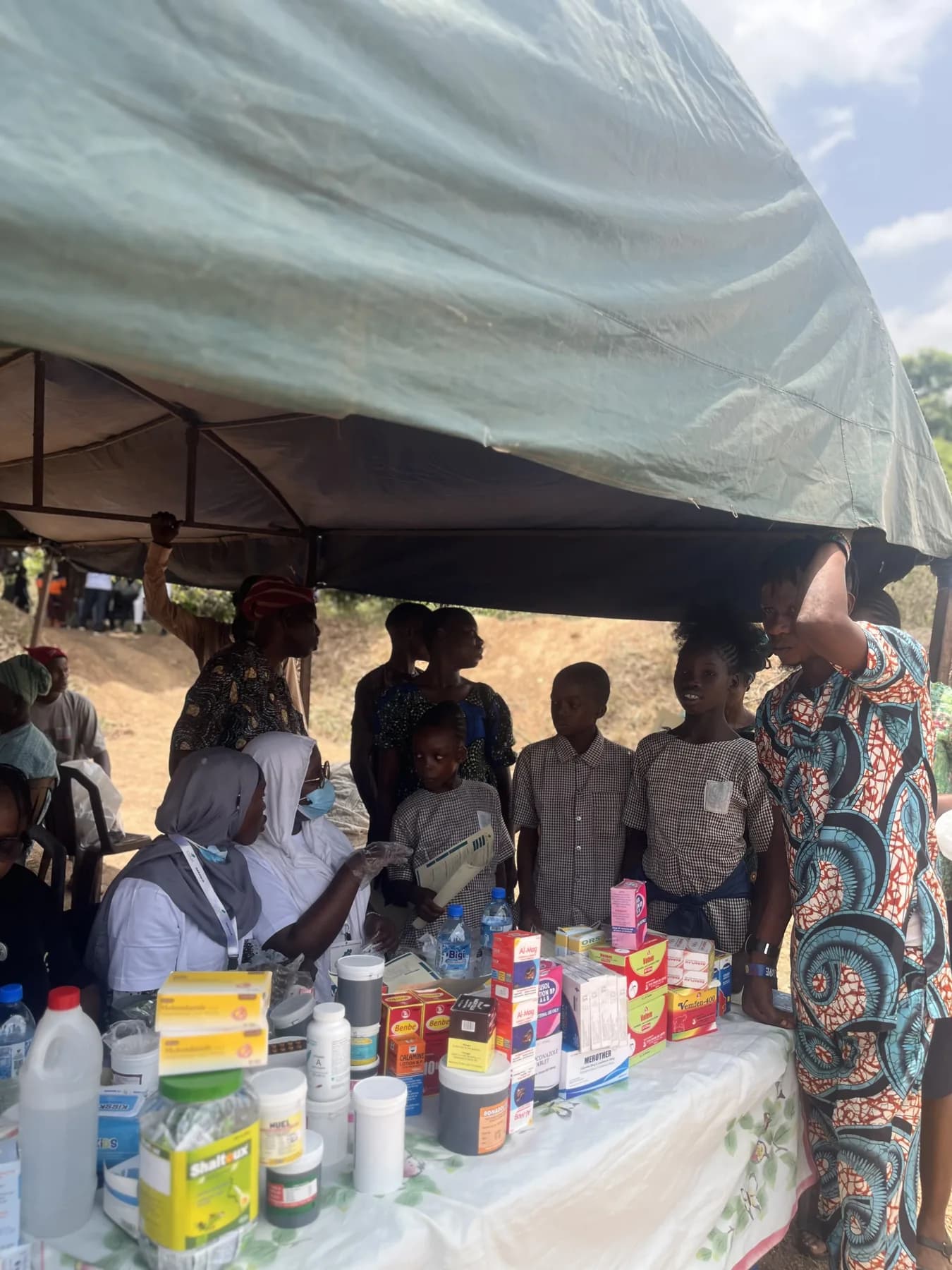 A covered medical-outreach station with supplies arranged on a table