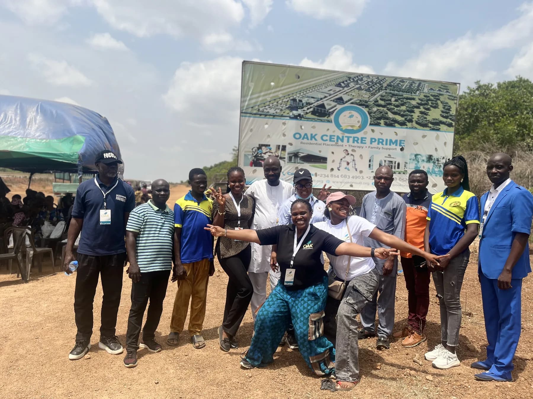 Medical-outreach volunteers gathered in front of the OAK Centre Prime site board