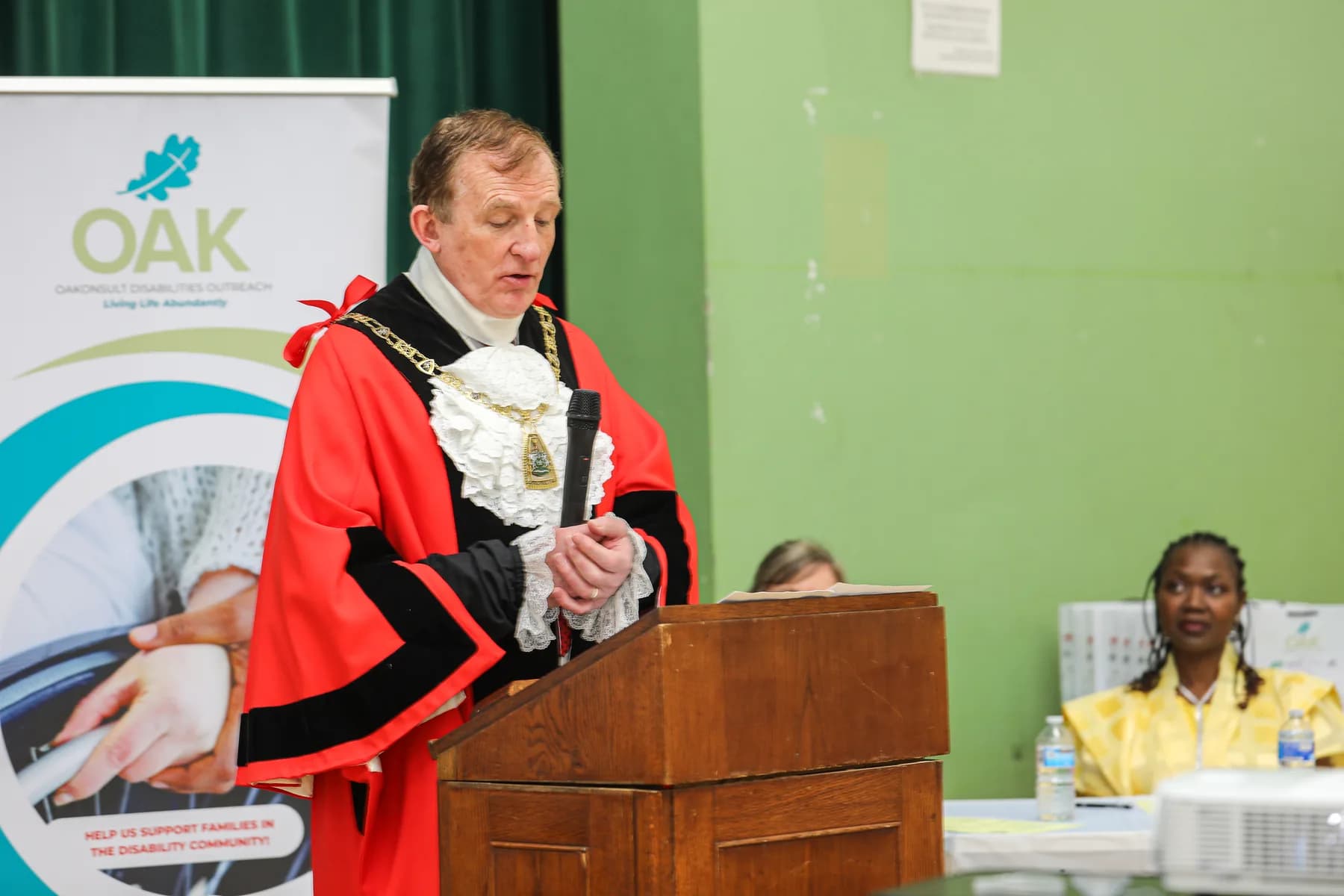 A civic guest speaking at a lectern during the Project ME celebration
