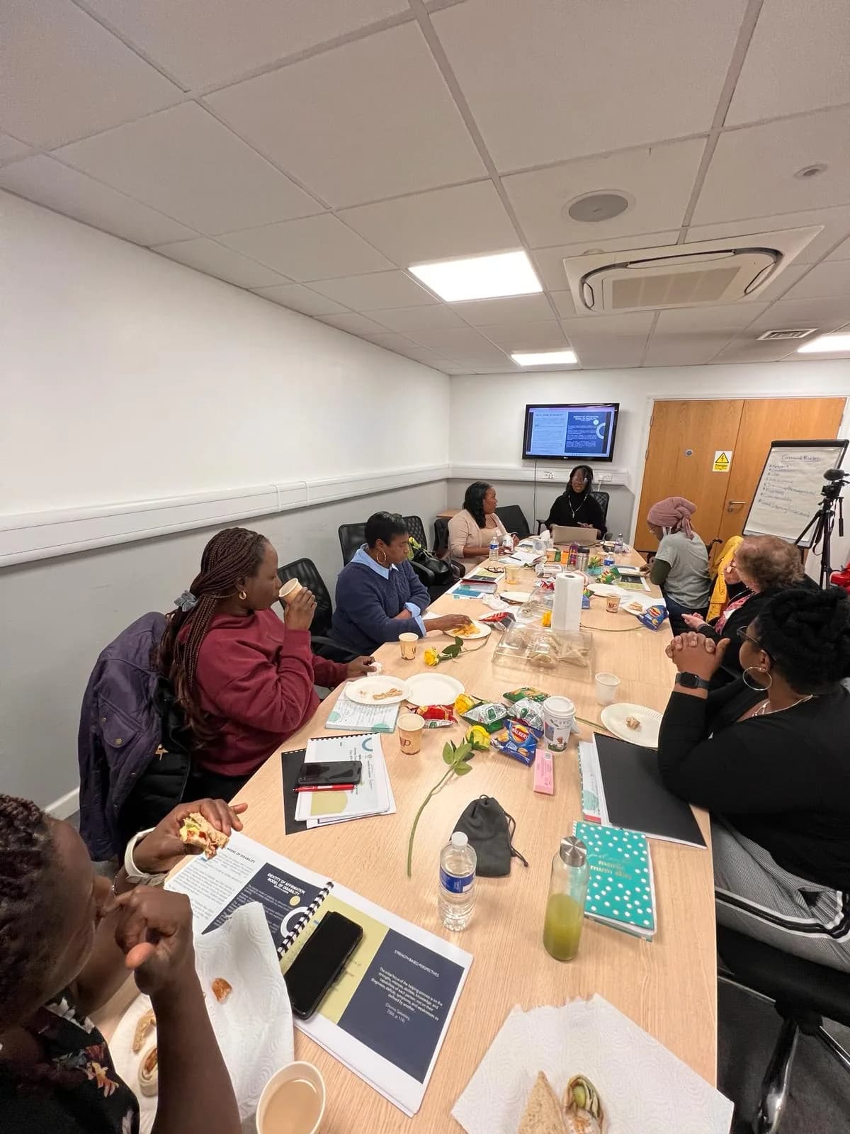 Project ME participants sharing a meal and discussion around a meeting table